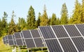 Solar panel collectors in forest, coniferous trees background, clear sky above, closeup detail