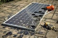 A solar panel lies on a brick road, possibly being dismantled or repaired, A broken solar panel being carefully disassembled for