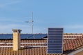 A solar panel is lifted by a technician as he prepares to mount it on the roof of a red-tiled house for a photovoltaic system Royalty Free Stock Photo