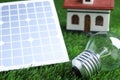 Solar panel, light bulb and house model on grass, closeup Royalty Free Stock Photo