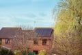 Solar panel on a red roof house, trees and blue sky. Alternative green energy concept. Selective focus, copy space Royalty Free Stock Photo