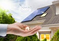 Solar panel on roof of house and coins in hand. Concept of money saving and clean energy Royalty Free Stock Photo