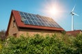 Solar panel on a roof of a house and wind turbins arround Royalty Free Stock Photo