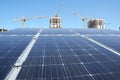 Solar panels against cranes construction. Renewable energy and industrial construction growth and global construction industry and