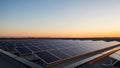 Solar panels arranged on a flat rooftop capture the sunset horizon Royalty Free Stock Photo