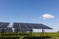 Solar panels in a field lined up against a cloudy blue sky on a sunny day. Royalty Free Stock Photo