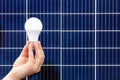 Solar panels. Hand holding white bulb against solar panel, solar station. Idea concept of alternative energy, technology, Royalty Free Stock Photo