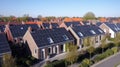 Solar panels are installed on the tiled roofs of a row of modern houses in a suburb with green streets under a blue sky Royalty Free Stock Photo