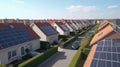 Solar panels are installed on the tiled roofs of a row of modern houses in a suburb with green streets under a blue sky Royalty Free Stock Photo