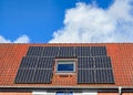 Solar panels of a photovoltaic powerplant at a red tiled roof