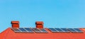 Solar panels on the red tiled roof of a building or house against a blue light sky Royalty Free Stock Photo