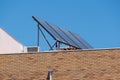 Solar panels on the roof of a brick apartment building with blue sky background. Royalty Free Stock Photo