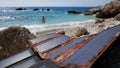 Solar panels set in stone. Girl tourist bathes in the sea Royalty Free Stock Photo