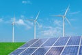 Solar panels with wind turbines generating electricity over blue sky background. Royalty Free Stock Photo