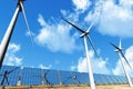 Solar panels and Wind Turbines under cloudy blue s