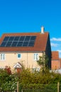 Solar photovoltaic panel array on house roof against a blue sky