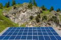 Solar photovoltaic panels against the backdrop of rocky mountains covered with green plants and trees Royalty Free Stock Photo