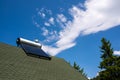 Solar water heater boiler on green rooftop, blue sky with white clouds Royalty Free Stock Photo