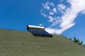 Solar water heater boiler on green rooftop, blue sky with white clouds Royalty Free Stock Photo