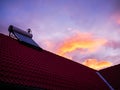 Solar water heater boiler on rooftop, sunrise, cold morning, orange clouds on blue sky