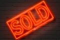 Sold, neon sign on brick wall