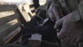 A soldier in a camouflage reloads an assault rifle magazine. Close up of hands. Slow mo. War time.