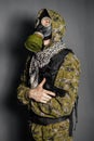 A soldier in camouflage uniform, body armor, in a gas mask with a hood on his head, holds a gun in his hands. Royalty Free Stock Photo