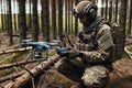 A soldier in a camouflage uniform with a control panel and a drone in the forest