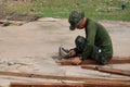 A soldier, a carpenter, is hammering wood. in house building, outdoor, carpentry work