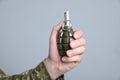 Soldier holding hand grenade on light grey background, closeup. Military service Royalty Free Stock Photo