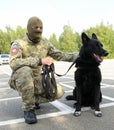 Soldier of KORD unit (Ukrainian SWAT) in uniform and his police dog sitting on a ground Royalty Free Stock Photo