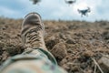 soldier legs laying on the dirt with flying drones in the sky above