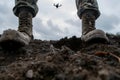 soldier legs standing on the dirt and drone in the sky above