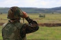 The soldier looks through binoculars. Back view, selective focus and blurred green nature background