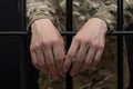 Soldier in military uniform behind bars against a black background. Concept: court martial, refusal to mobilize, crime in the army Royalty Free Stock Photo