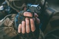 The soldier in the performance of tasks in camouflage and protective gloves holding a pistol