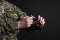 Soldier pulling safety pin out of hand grenade on black background, closeup. Military service Royalty Free Stock Photo