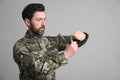 Soldier pulling safety pin out of hand grenade on light grey background. Military service Royalty Free Stock Photo