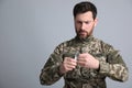 Soldier pulling safety pin out of hand grenade on light grey background. Military service Royalty Free Stock Photo