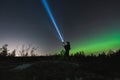 A soldier with a rifle and weapon flashlight in a night forest, sky with stars and northern lights