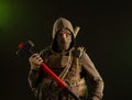 A soldier-saboteur rebel in military clothing with a weapon on a dark background holding a sledgehammer Royalty Free Stock Photo