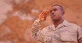 Soldier saluting against blurry brown map with red overlay