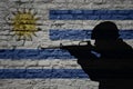 Soldier silhouette on the old brick wall with flag of uruguay country