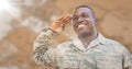 Soldier smiling and saluting against blurry brown map with flare