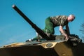 Soldier washes battle tank sitting on top of the tower