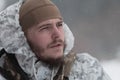 Soldier in winter camouflaged uniform in Modern warfare army on a snow day on forest battlefield with a rifle. Model