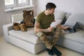 Soldier working on laptop online while holding paperwork