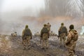 Soldiers in bulletproof vests and helmets on target practice with machine guns on a foggy day