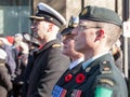 Soldiers from Canadian Army, two men, a woman, from Navy & ground forces, wearing remembrance poppy, standing on ceremony