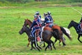 Soldiers in historical costumes ride horses and hold swords.